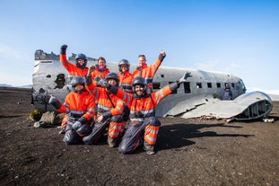 Group of ATV riders in orange suits posing by the DC-3 plane wreck on Iceland’s South Coast.