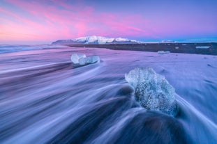 Una hipnótica imagen en la Playa de los Diamantes , con olas que fluyen entre bloques de hielo bajo un cielo púrpura.
