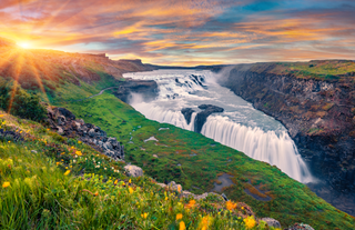 Gullfoss Waterfall cascades through a lush green canyon at sunset on Iceland’s famous Golden Circle Route.