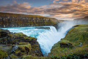 Gullfoss-vandfaldet i Den Gyldne Cirkel, Island, med levende blåt vand, der falder ned over klipperne ved solnedgang.