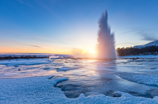 Strokkur geyser erupts at sunrise in Iceland’s Haukadalur geothermal valley on a crisp winter morning.