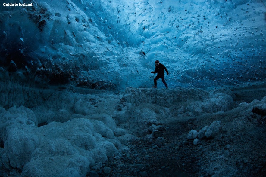 Traveler exploring a blue ice cave beneath Vatnajokull glacier in Iceland during winter