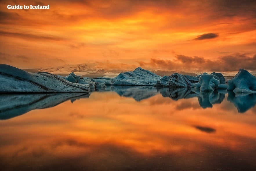 Icebergs floating on Jokulsarlon Glacier Lagoon during vibrant orange sunset in Iceland
